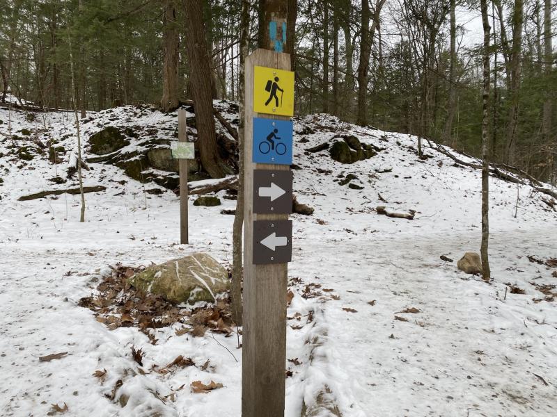 Trail markers indicating direction, the yellow hiking path, and the blue multi-use path.